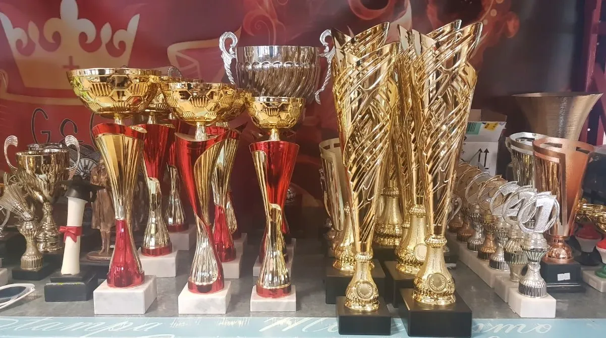 Scaffale di coppe e trofei dorati, rossi e argento per premiazioni