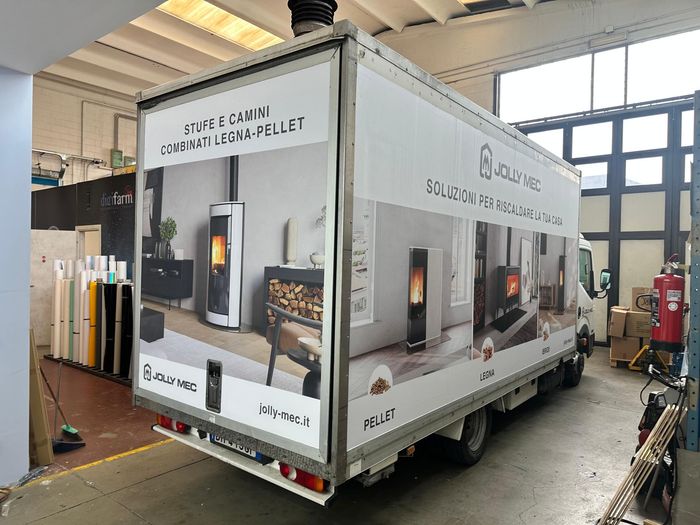 Cassone di un camion Jolly Mec con pannelli stampati di stufe e camini su fiancata e portellone