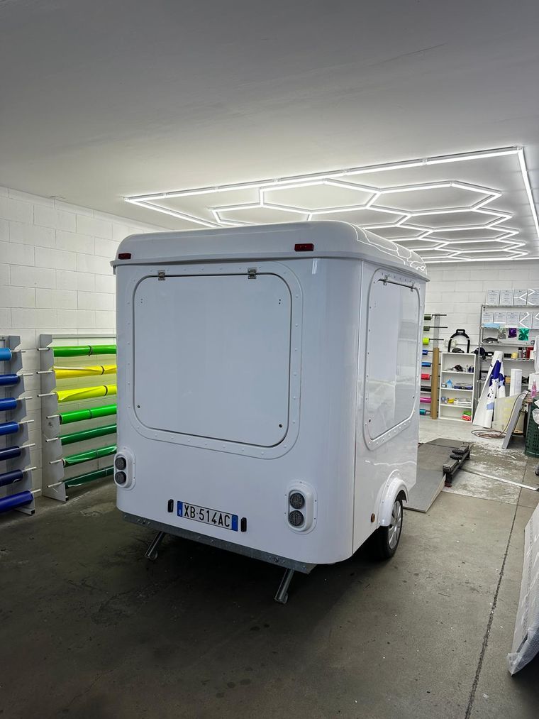 Rimorchio street food bianco senza grafiche, in sala wrapping accanto alle bobine di pellicola colorata